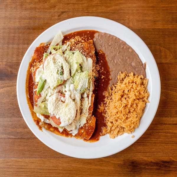 Enchiladas topped with lettuce, avocado, cheese, and sour cream, served with rice and refried beans.